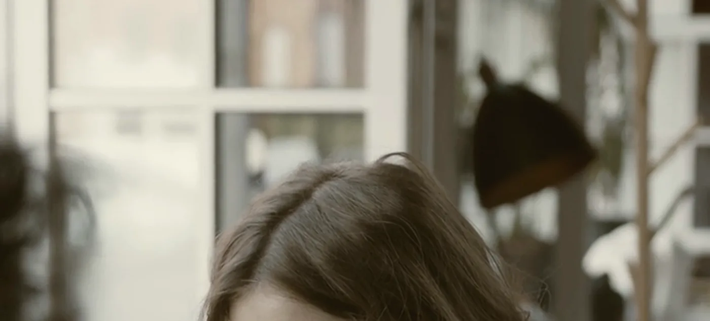 Someone with a coffee in a café window, mid-conversation.