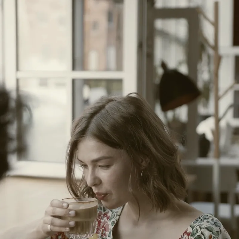 Someone with a coffee in a café window, mid-conversation.