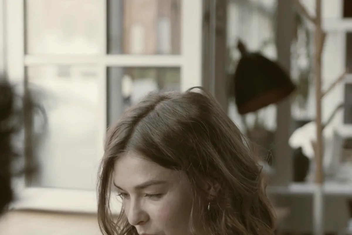 Someone with a coffee in a café window, mid-conversation.
