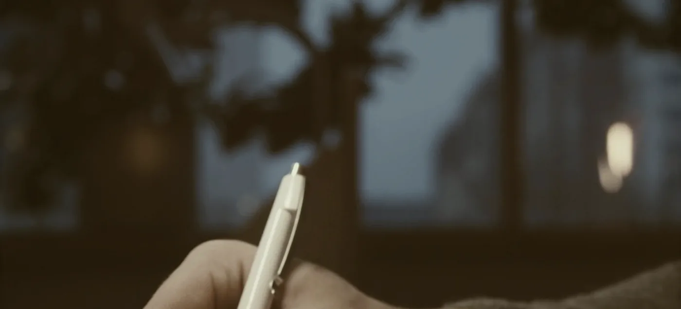 A hand writing a letter at a desk.