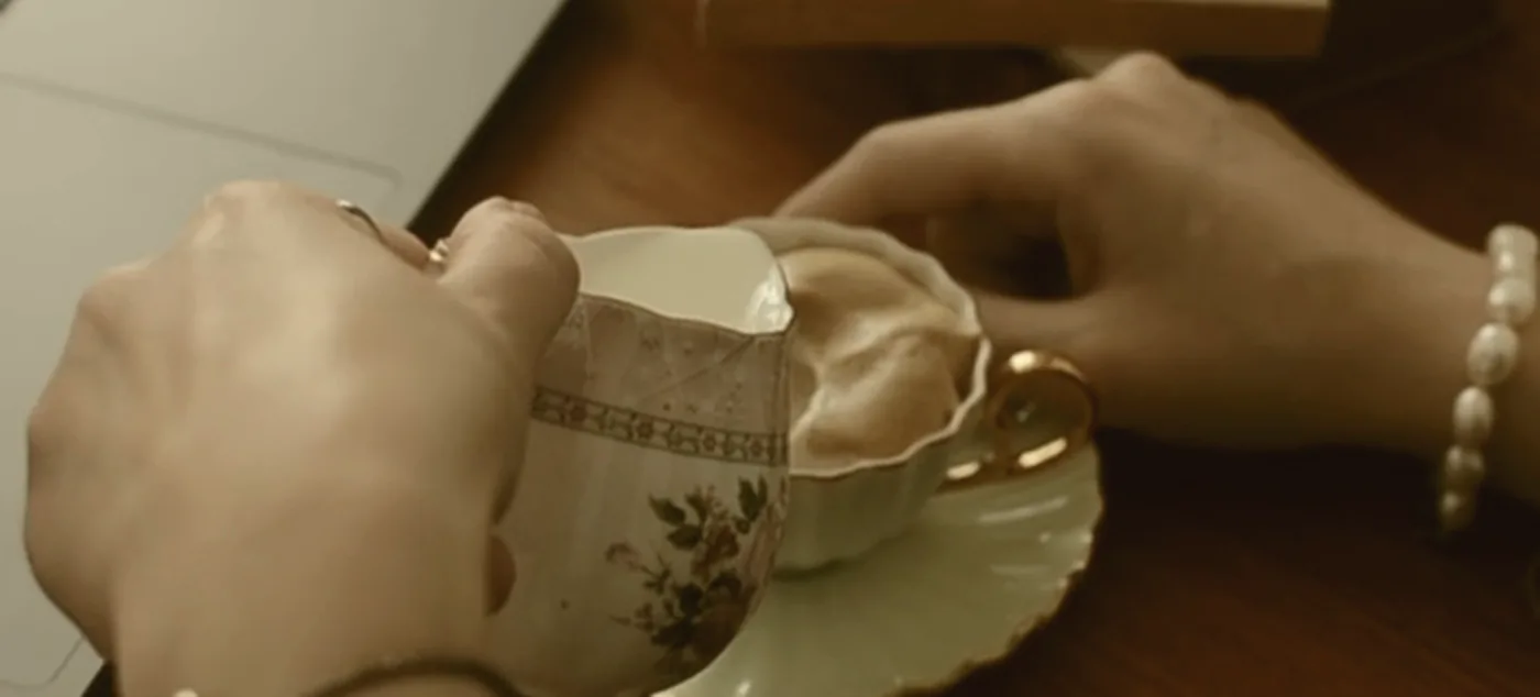 Two coffee cups on a table between two people mid-conversation.