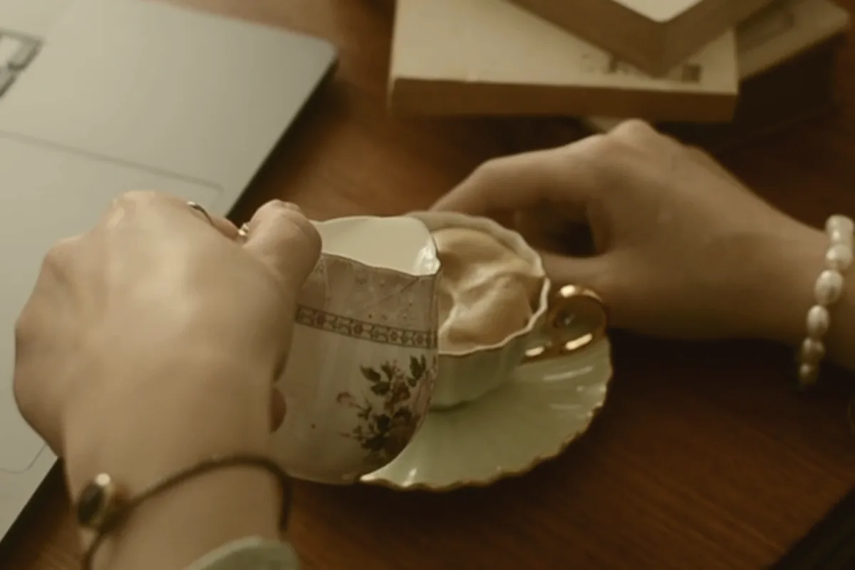 Two coffee cups on a table between two people mid-conversation.