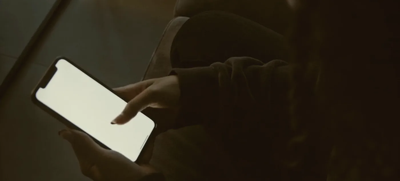 Hands holding a phone in a parked car at night.