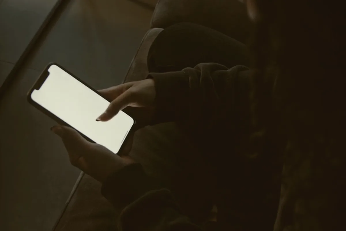 Hands holding a phone in a parked car at night.
