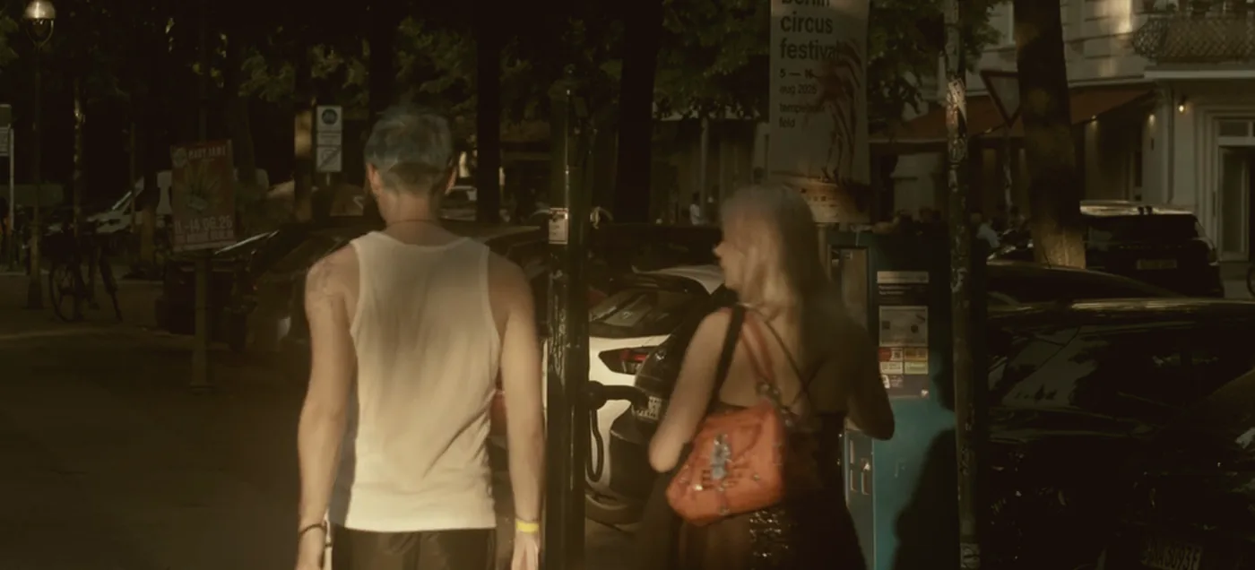 Two people walking away down a tree-lined street at dusk.