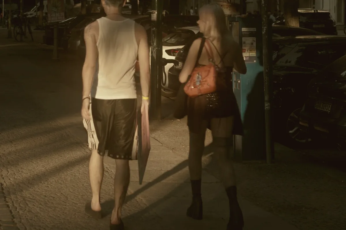 Two people walking away down a tree-lined street at dusk.