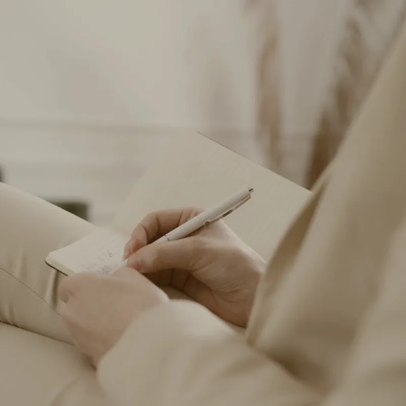 Hands writing a short note in a notebook.